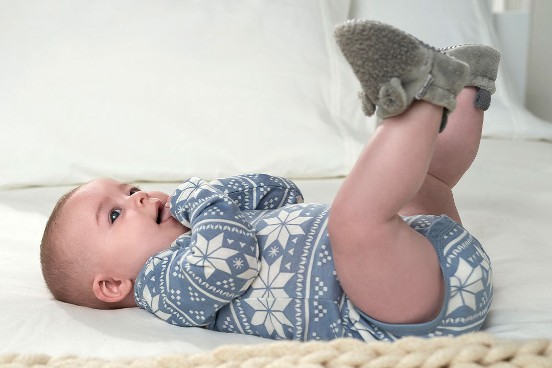 This little one looks adorable in a blue sweater, peacefully lying on its back. Winter boys booties complete the cozy winter ensemble!