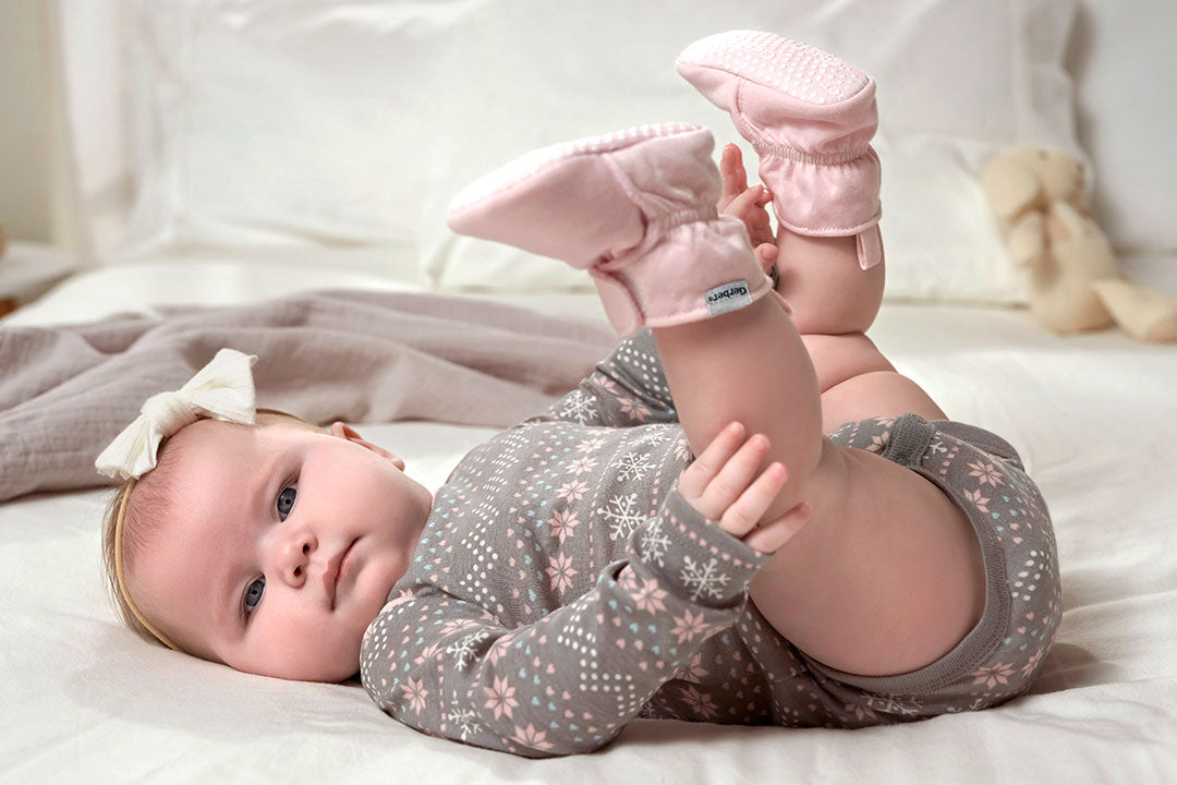 A cute baby girl in pink shoes lying on her back, enjoying the winter season. So adorable!