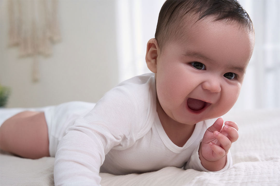 A close-up shot of a contented baby's face, radiating joy while lying on a bed.